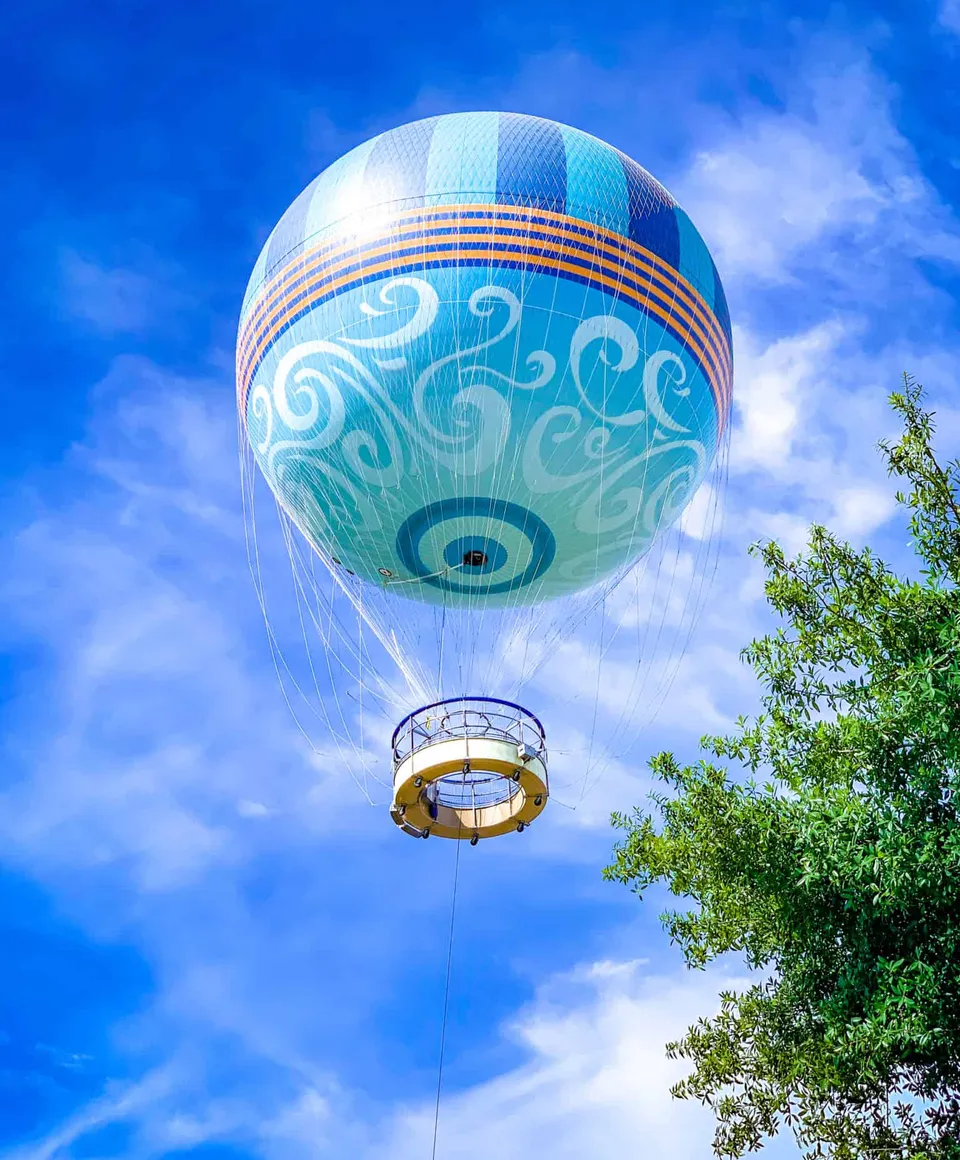 Disney Springs Aerophile balloon floating above Florida trees and bright blue sky